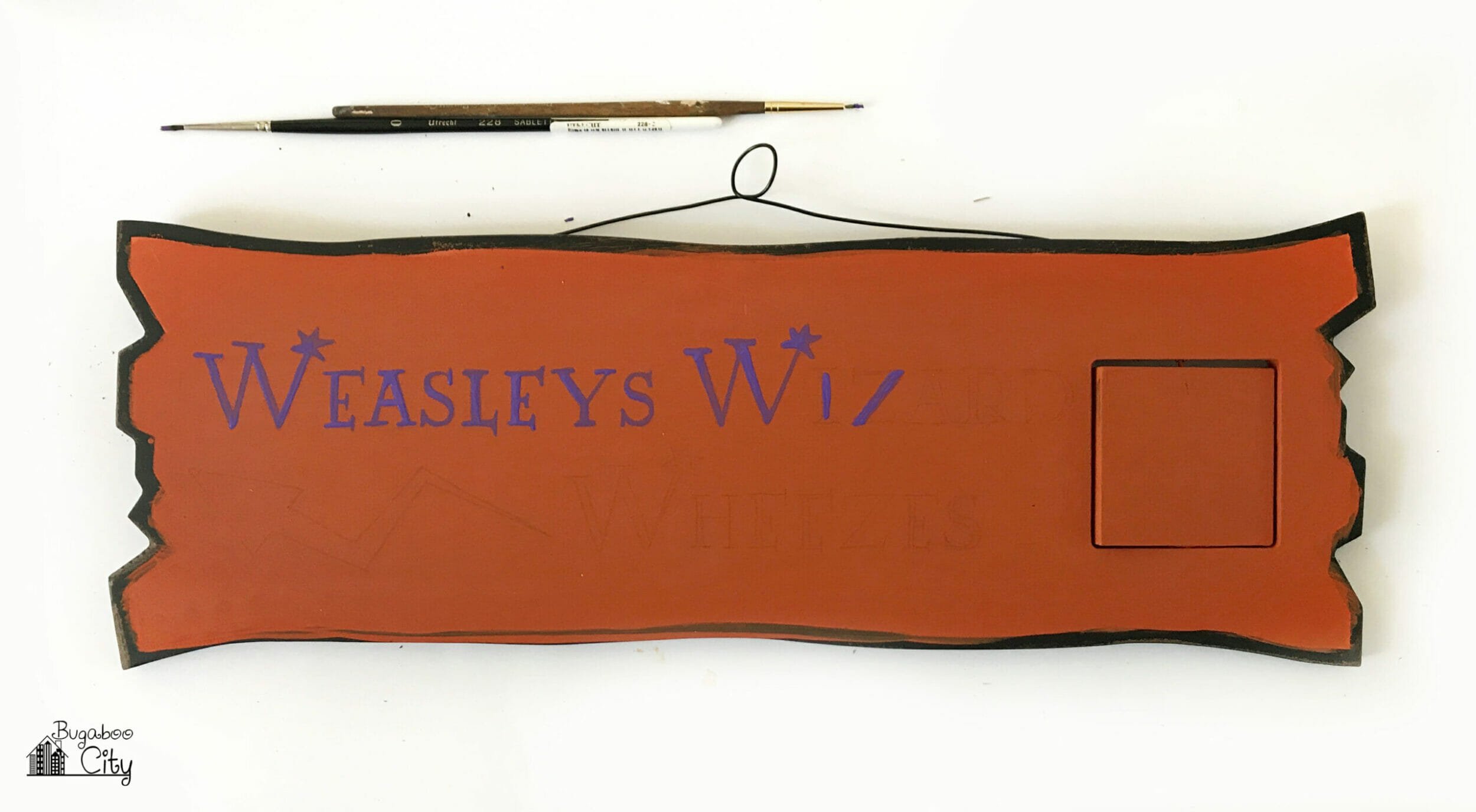 The words are painted on the sign following pencil lines.
