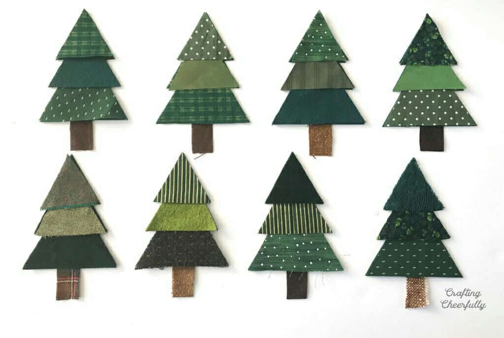 Eight Christmas tree pennants lay on a white table.