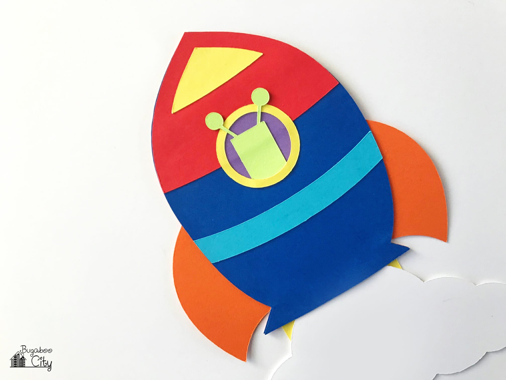Paper alien is added to the window of the rocket ship.