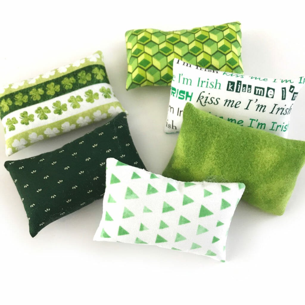 A group of green and white pillows of different patterns.