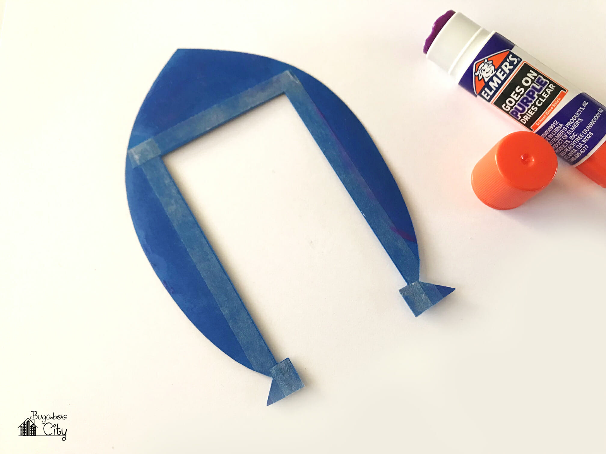 The back side of a blue rocket ship piece is covered with adhesive.