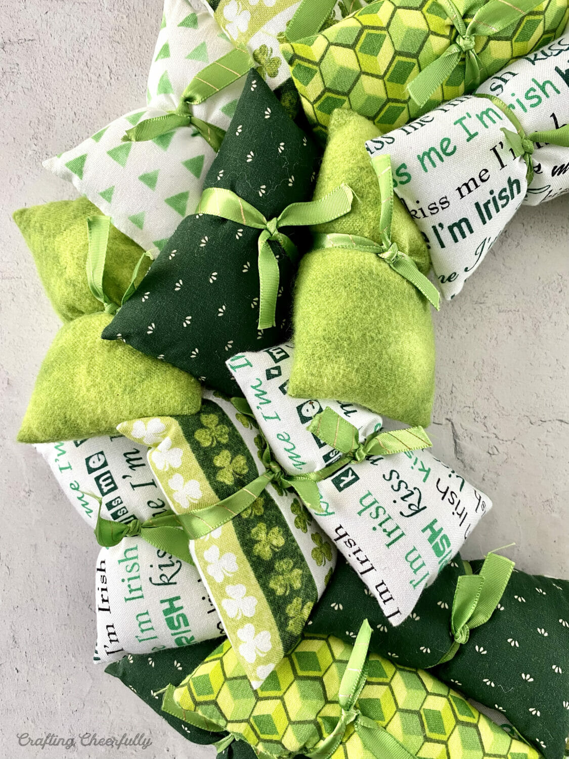 Green and white fabric pillows are tied with ribbon to form a wreath.
