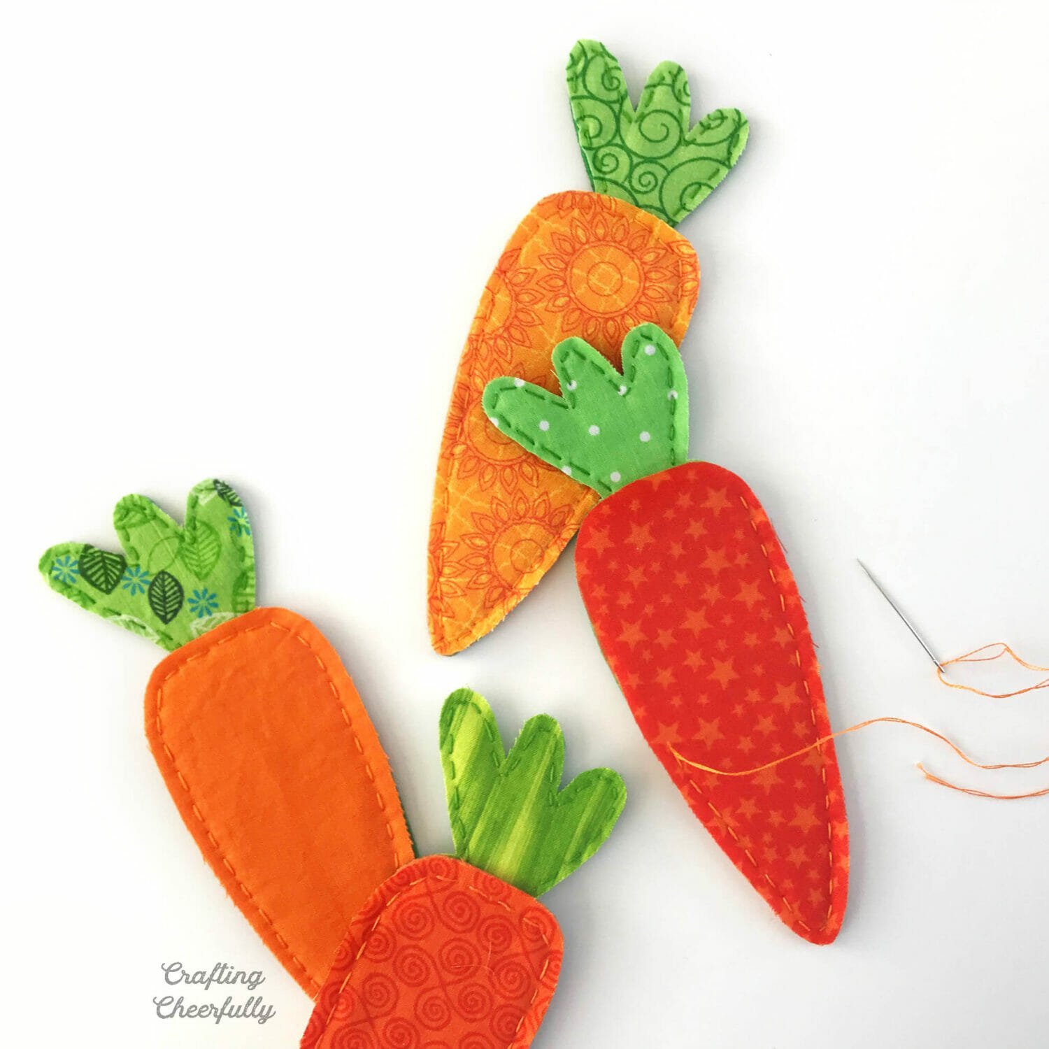 Felt and fabric carrots partially stitched with embroidery floss.