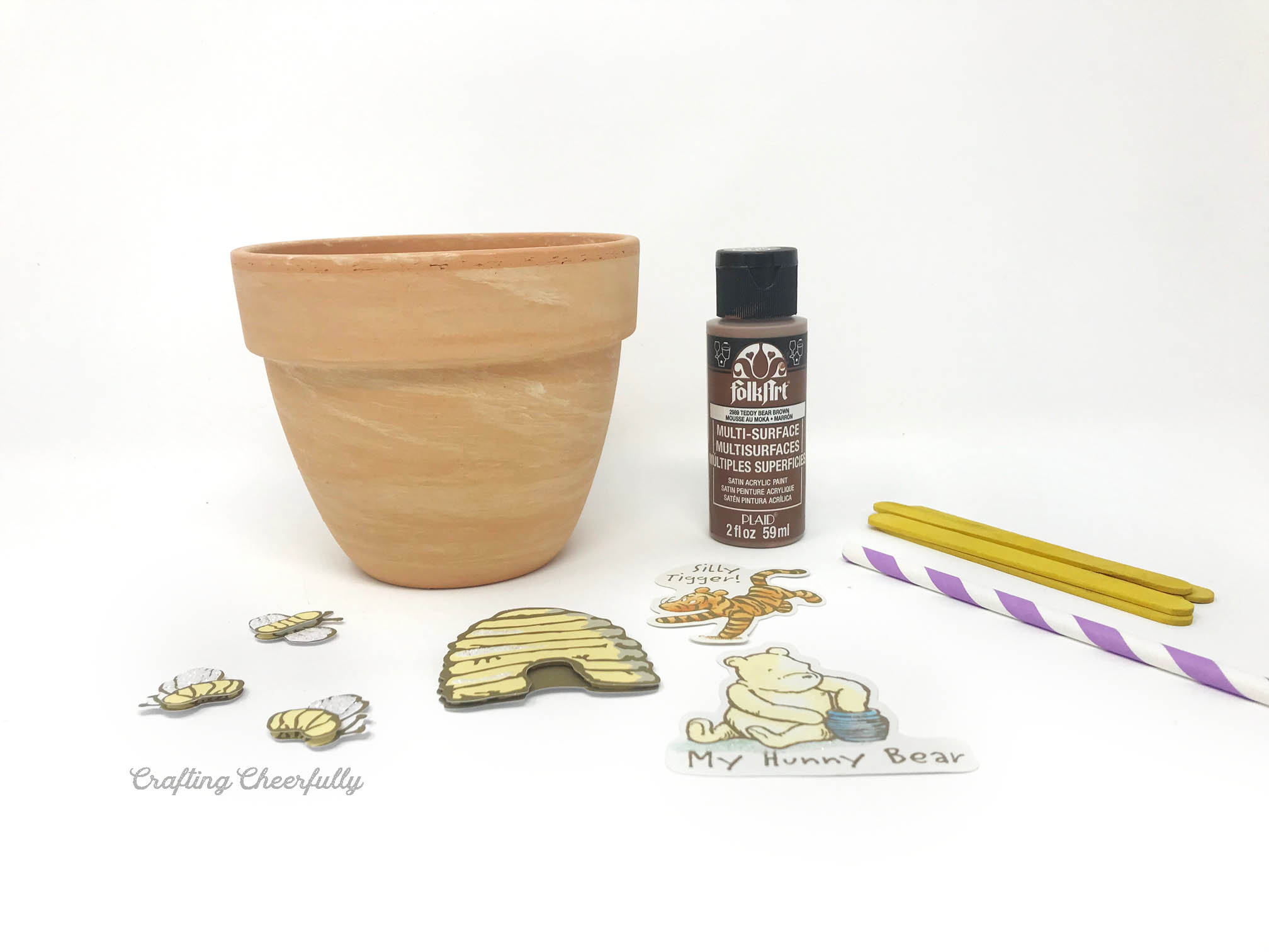 Supplies needed including a terra cotta pot, paint, popsickle sticks and Pooh bear embellishments.