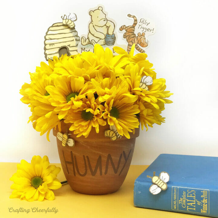 Terra cotta honey pot with yellow flowers and classic Winnie the Pooh characters.