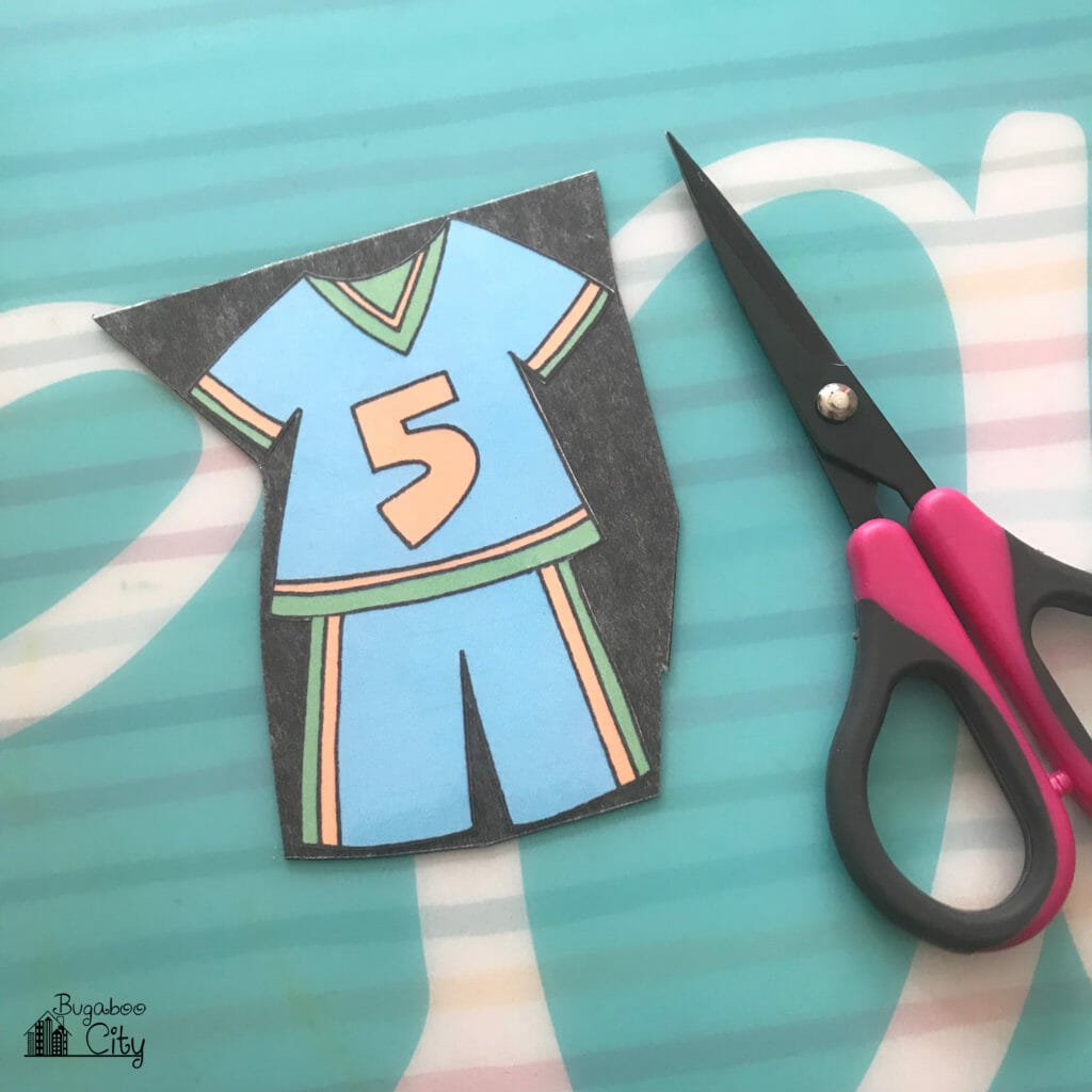 Paper doll clothing cut out and applied to a piece of magnet.