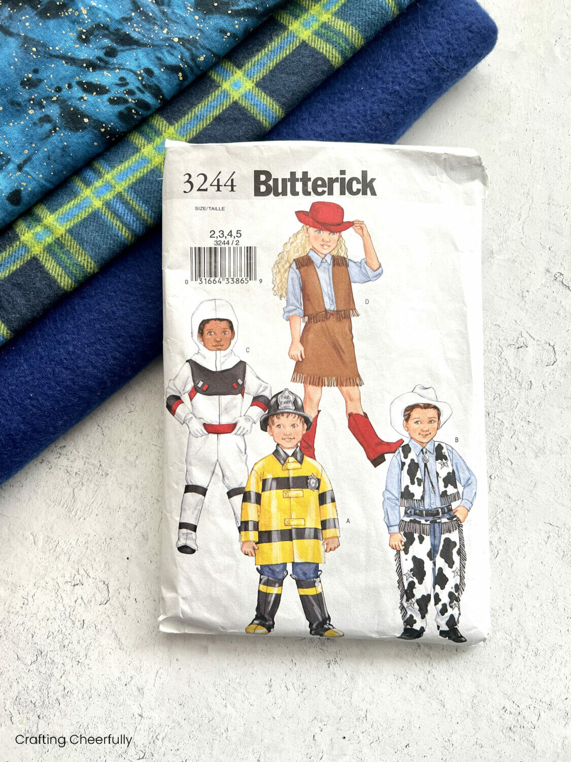 Butterick Pattern 3244 lays on a stack of blue and green fabrics.
