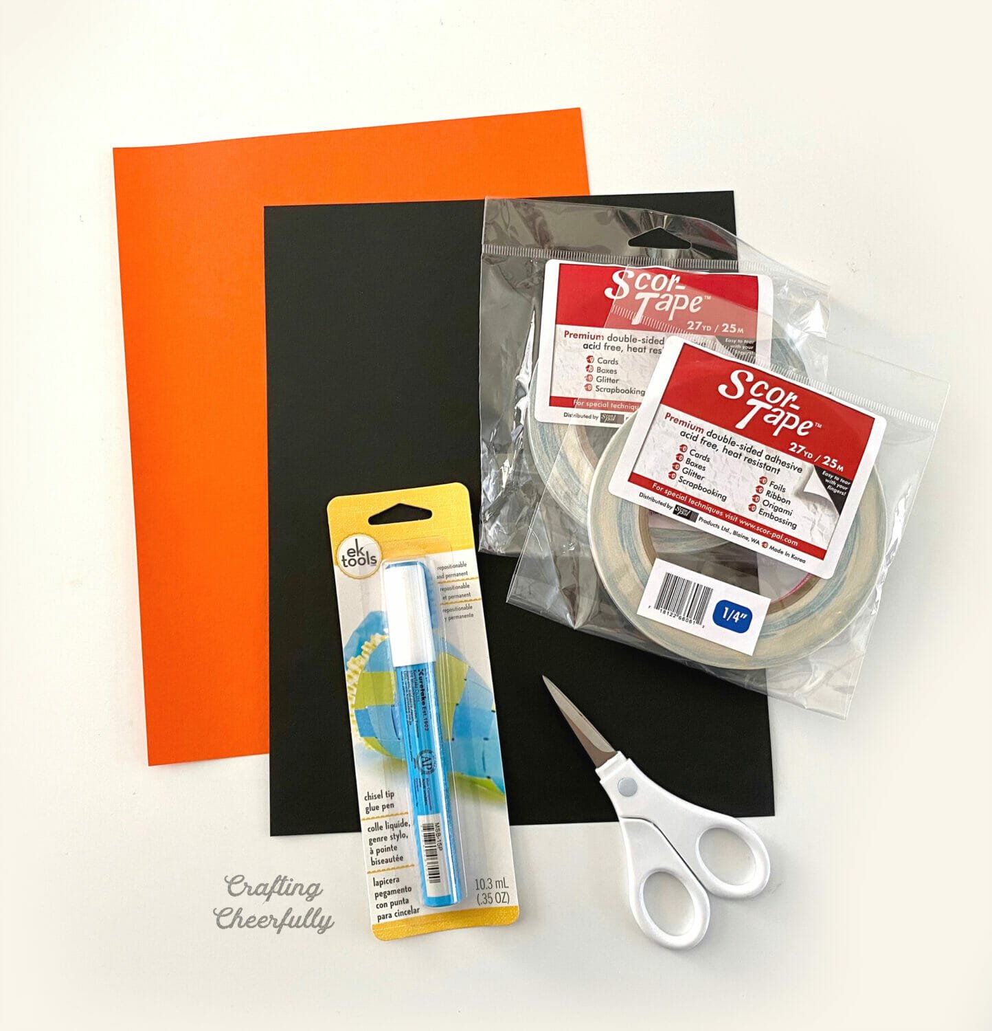 Supplies needed for Halloween treat boxes including paper, double-sided tape, scissors and glue pen.