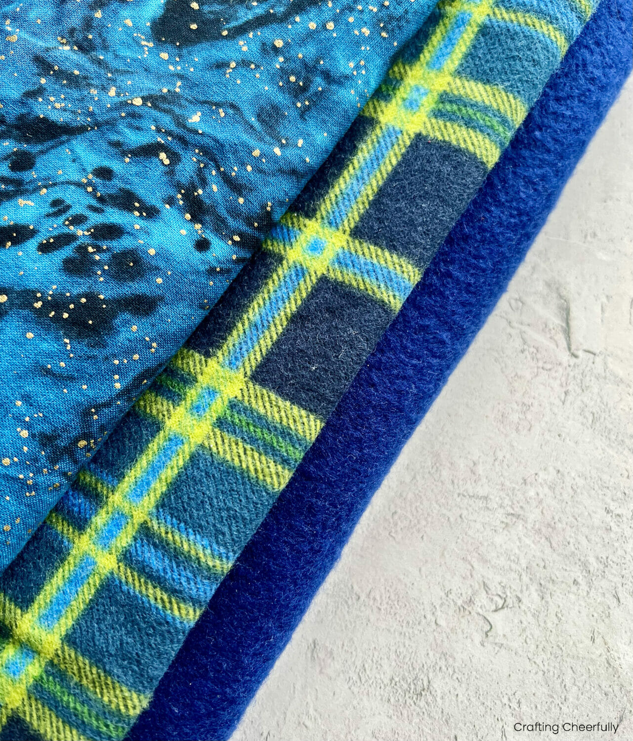 Fabrics used to make the coat including a blue fleece, blue and green plaid flannel and sparkly glue galaxy printed cotton.