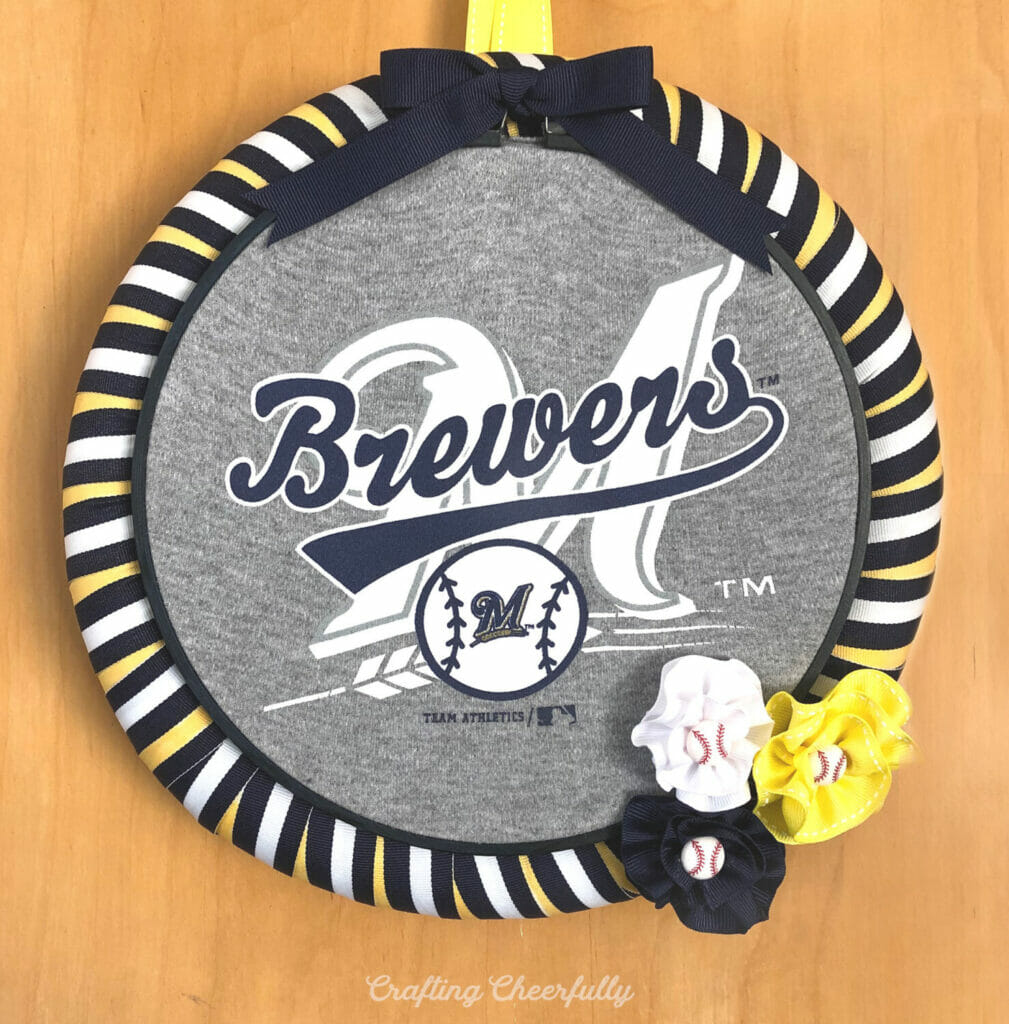 Fabric baseball wreath that reads "Brewers" on the front with striped ribbon around it.