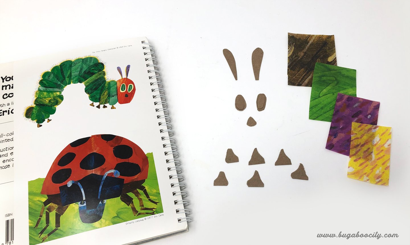 A book is open to the picture of the Hungry Caterpillar and small details like feet and eyes are cut from cardboard.