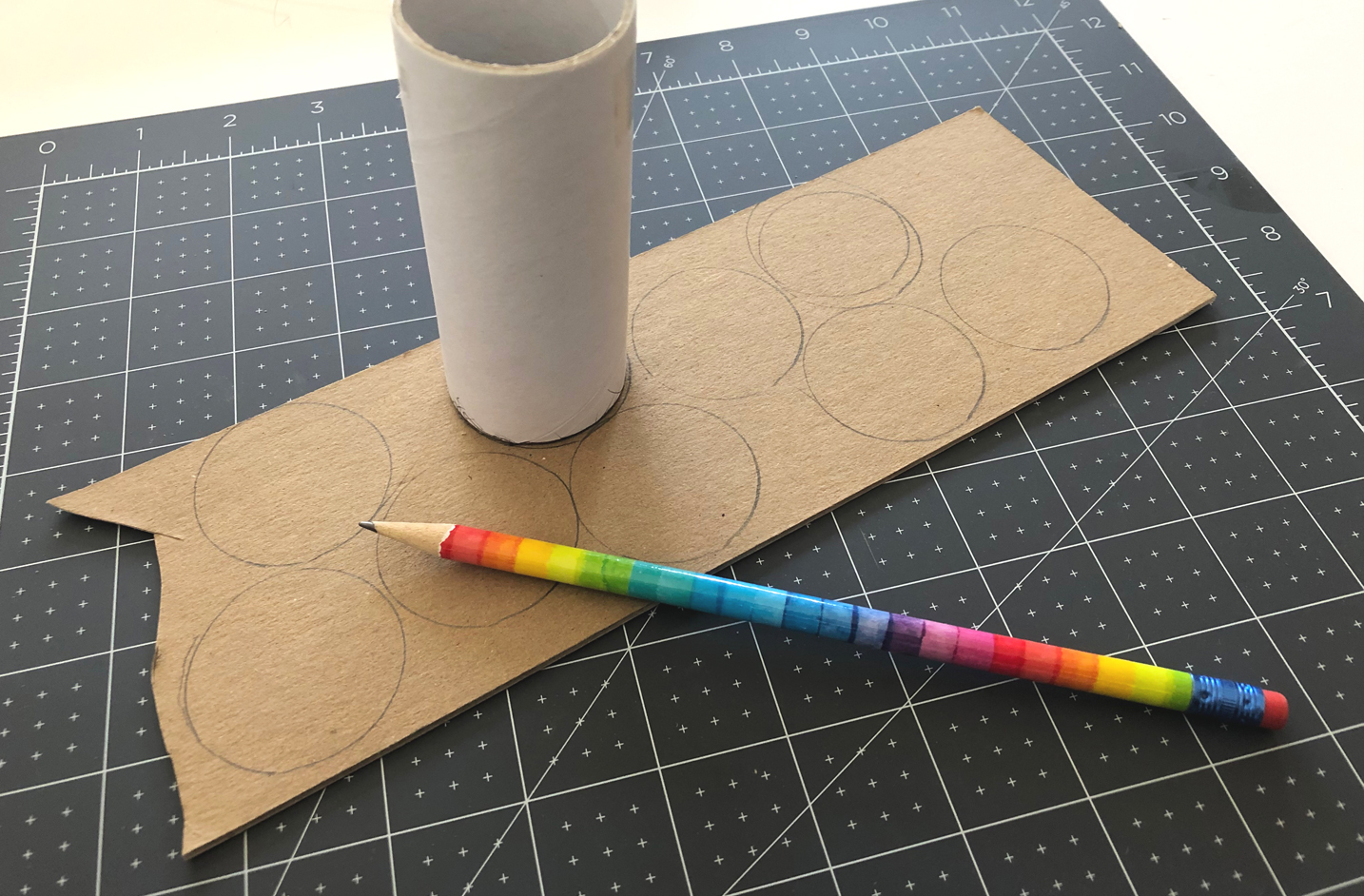 Pencil traces around the bottom of a cardboard tube on piece of cardboard.
