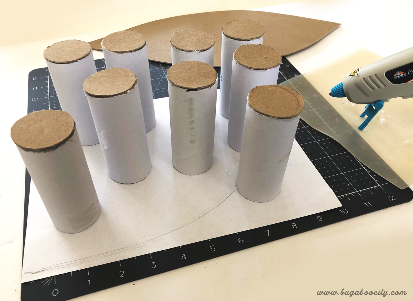 Cardboard circles are glued to the top of white cardboard tubes.