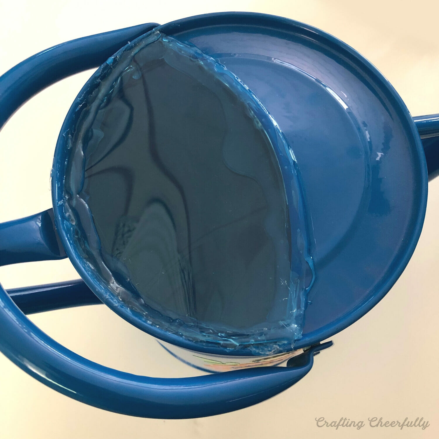 Opening of watering can is covered in blue plastic.