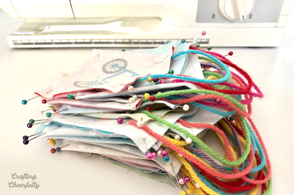 A stack of pinned ornaments sit in front of a sewing machine.