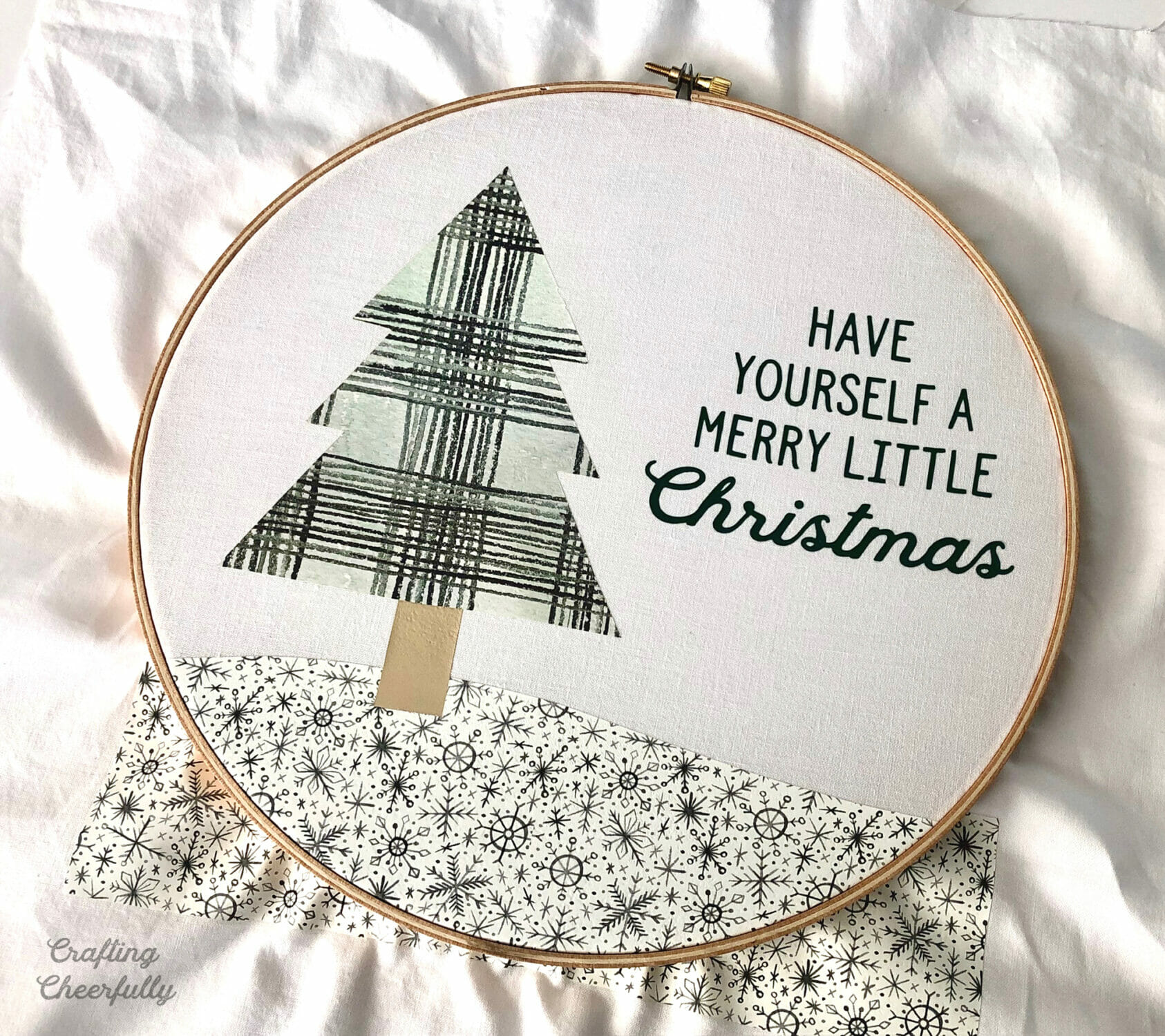 An embroidery hoop frames the winter scene created from HTV.