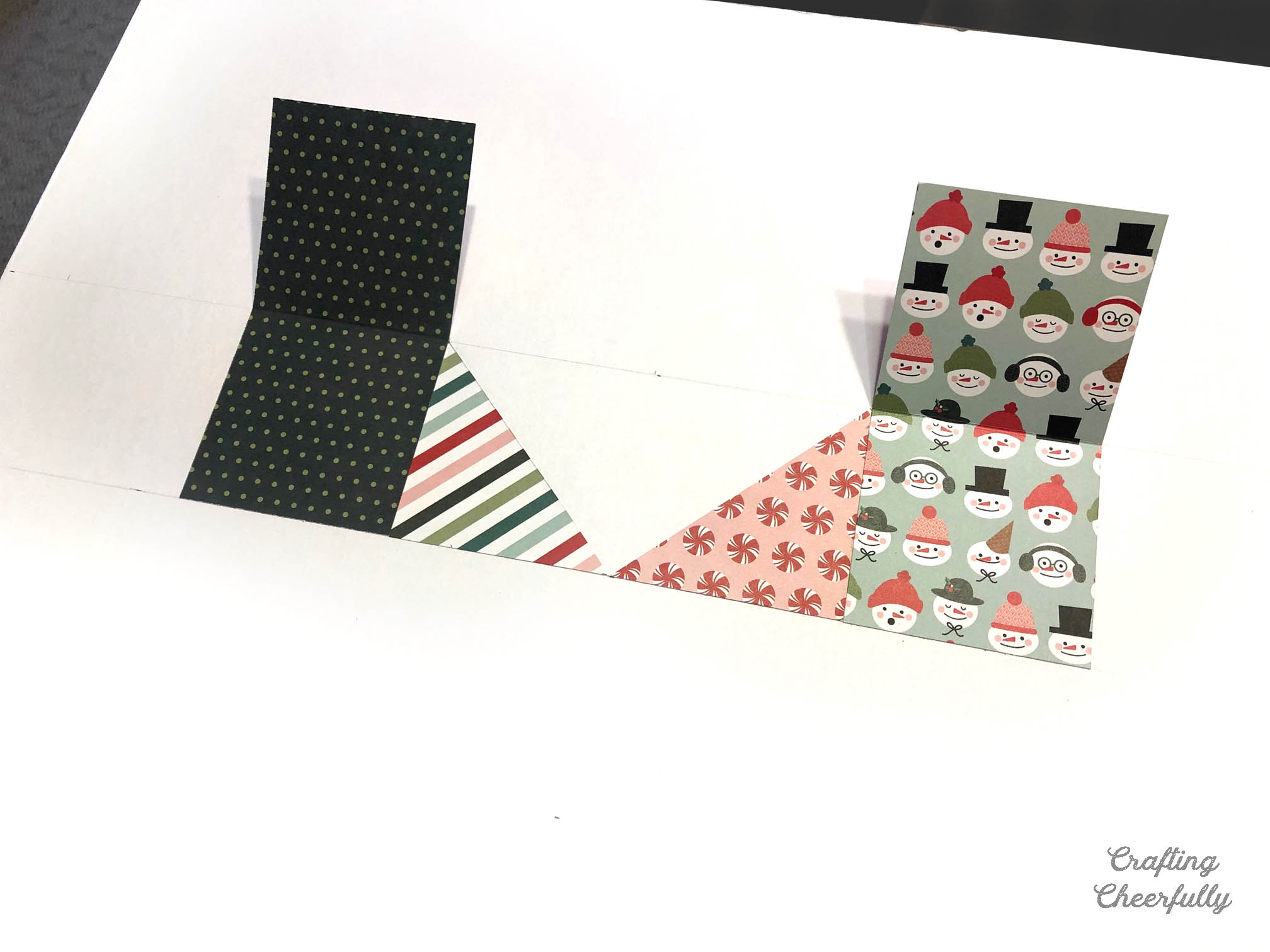 The first pieces of paper are glued to the foam board to form the beginning of a heart.