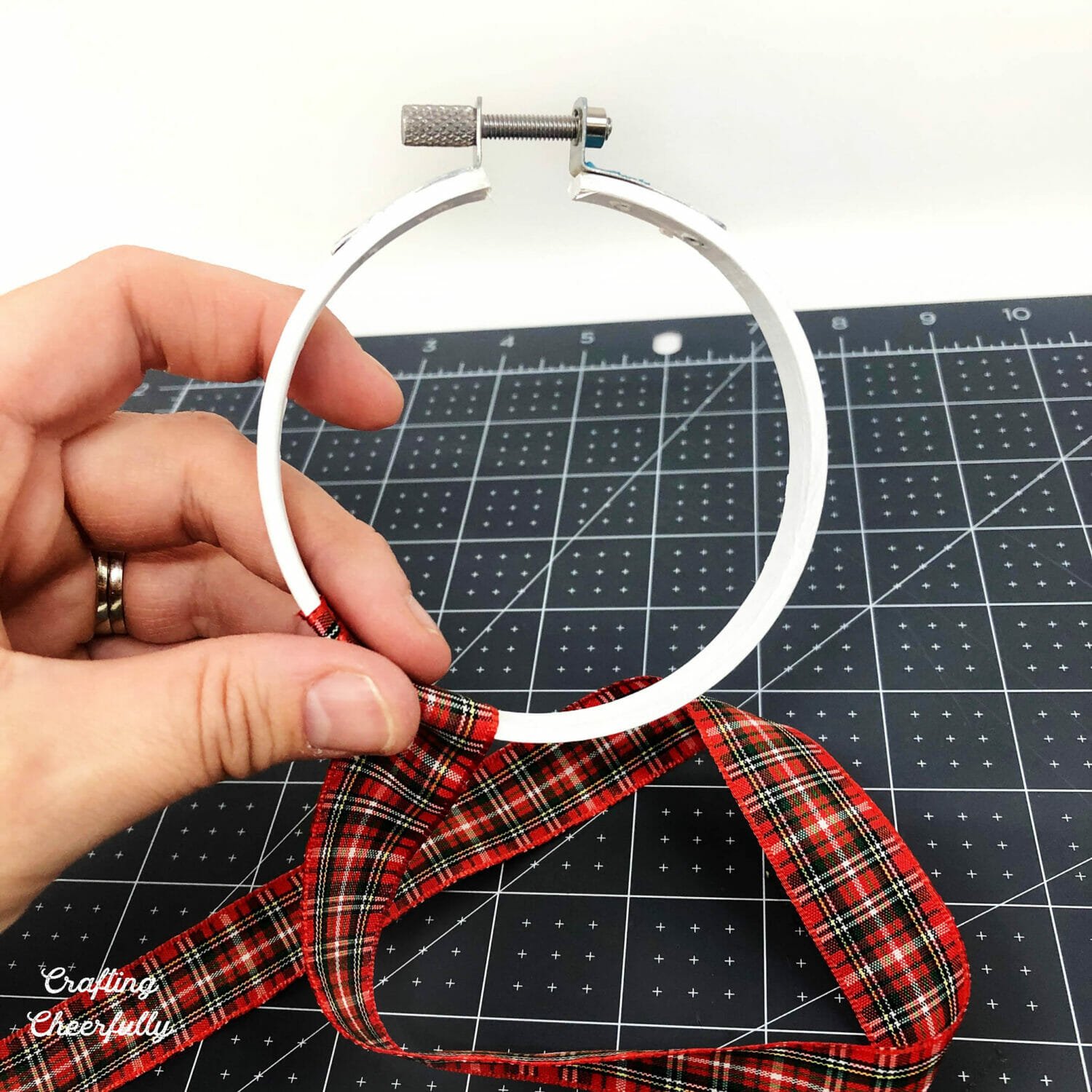 Embroidery hoop is painted white and the bottom of the hoop is wrapped in ribbon.