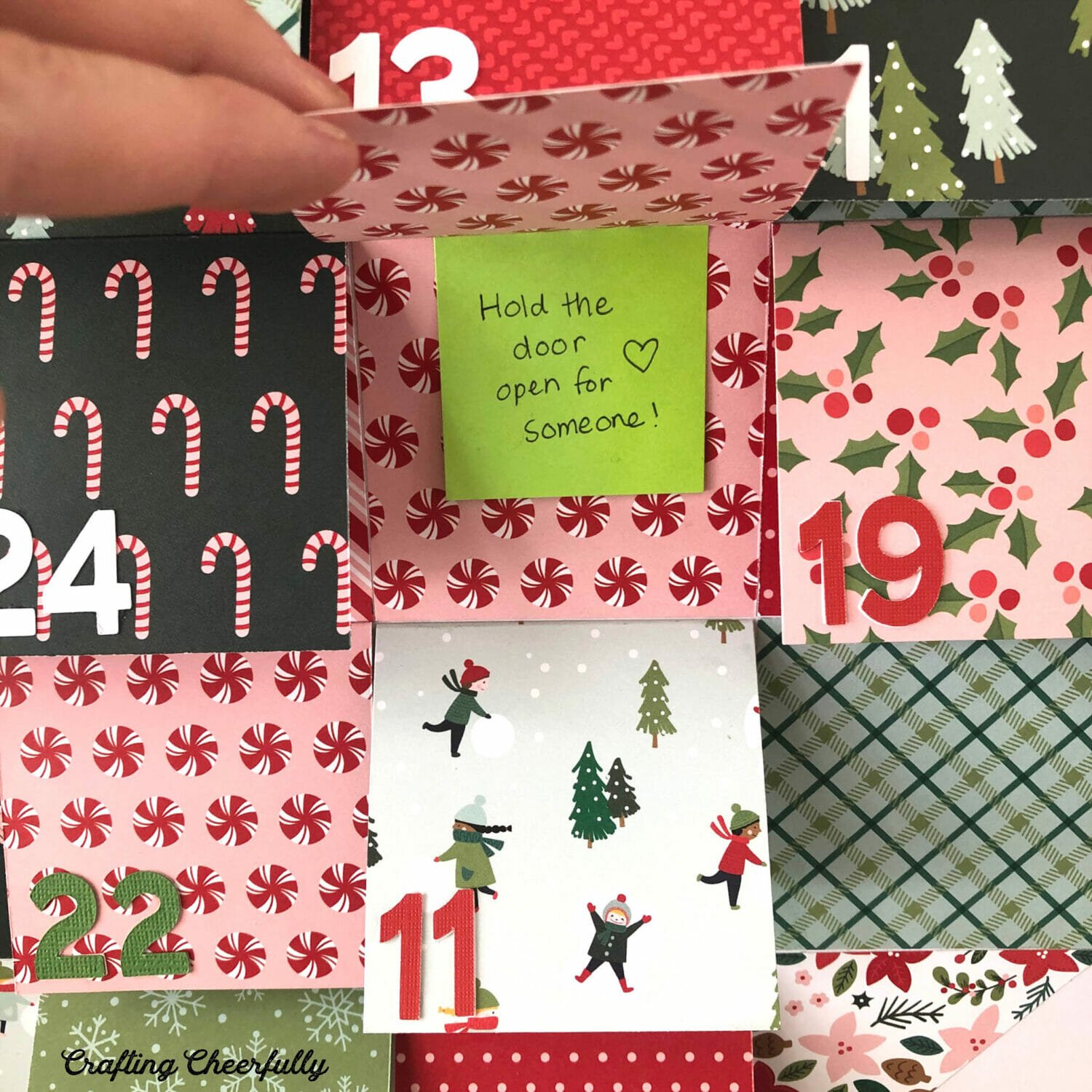 Flap lifted on the kindness advent calendar shows a post-it note that reads "Hold the door open for someone".