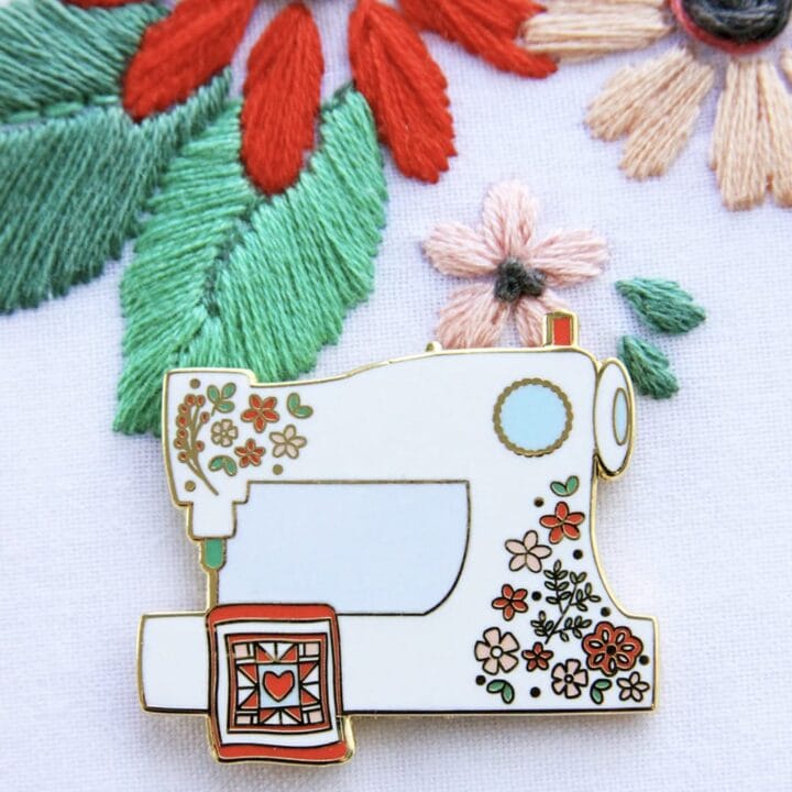 A sewing machine needle minder on a hoop with embroidered flowers.