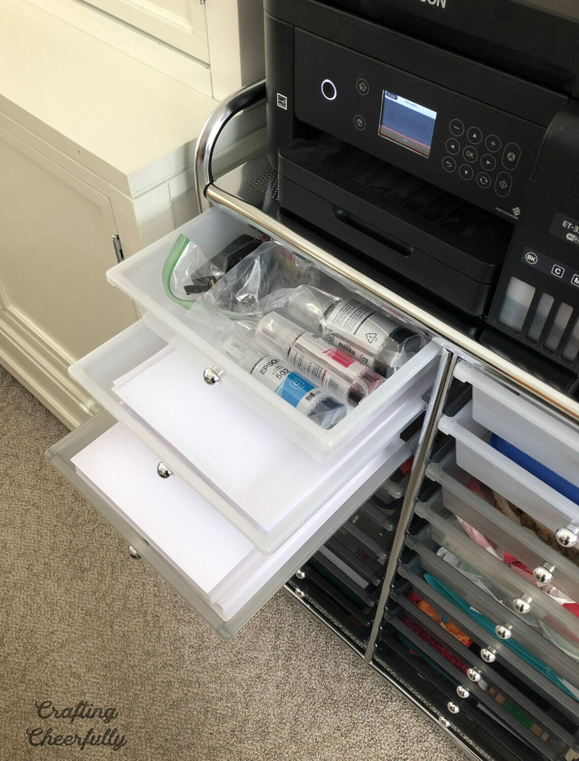 The top few drawers of the storage cart show ink supplies and paper.