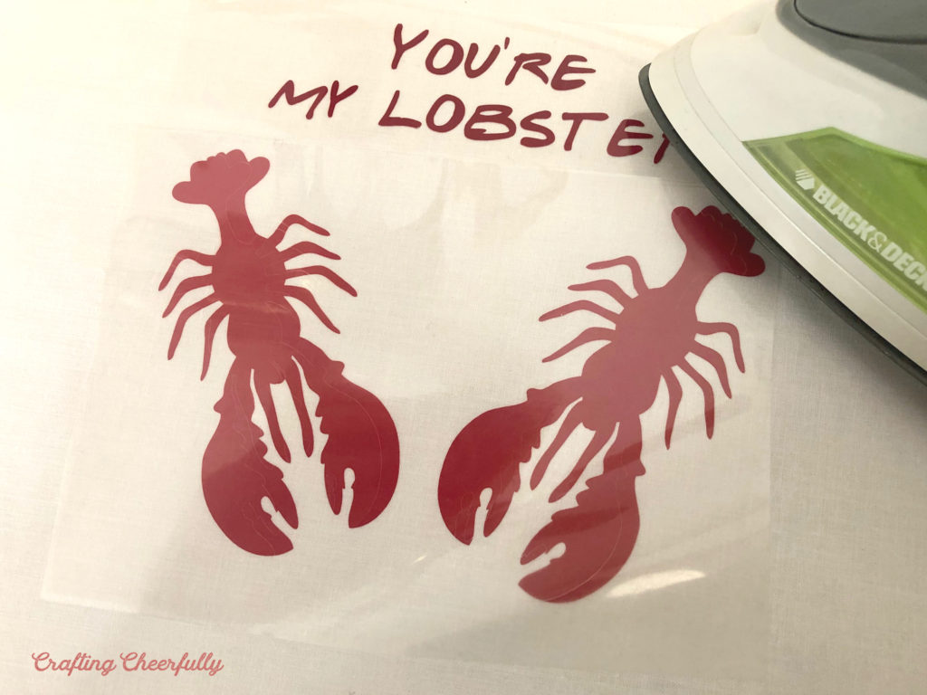 An iron presses the lobster image on white cotton.