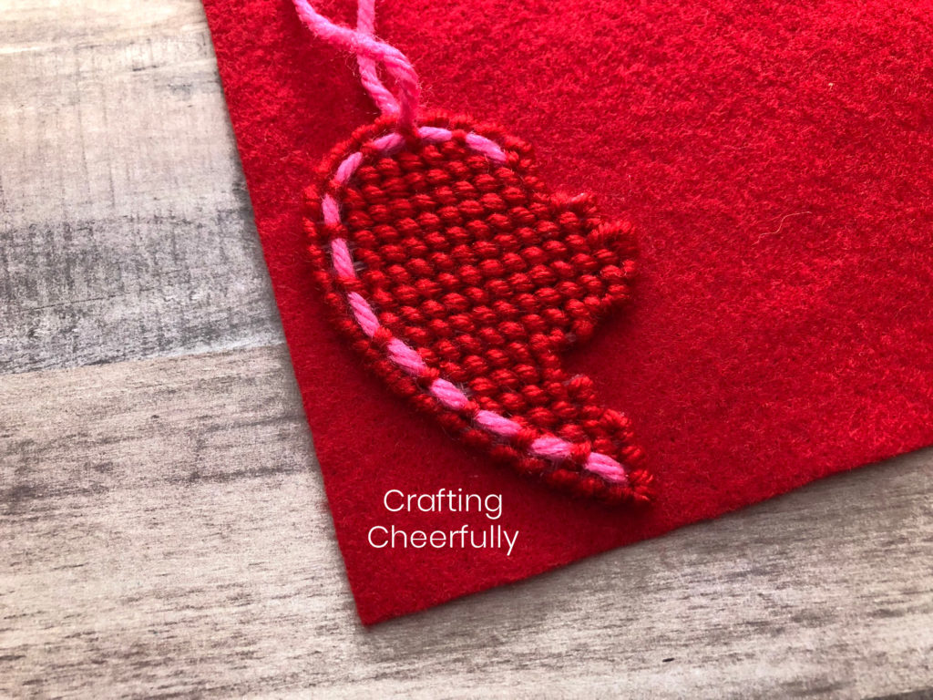 The left side of the heart necklace laying on top of red felt.