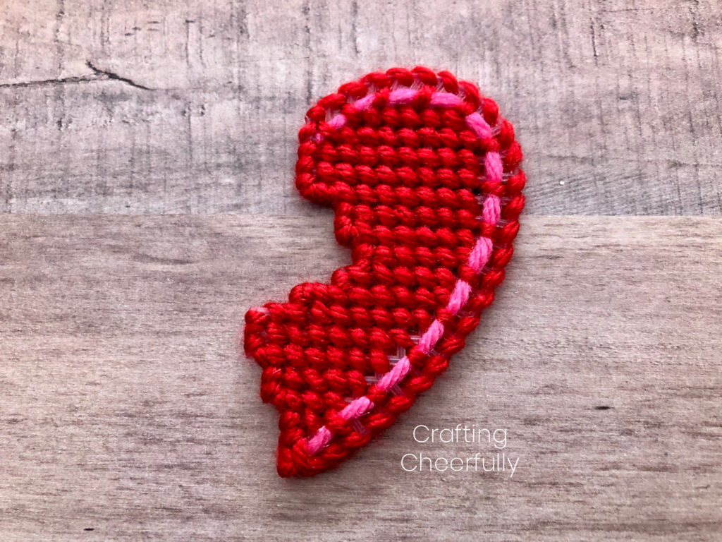 Right side of the plastic canvas heart completely covered in yarn stitches.