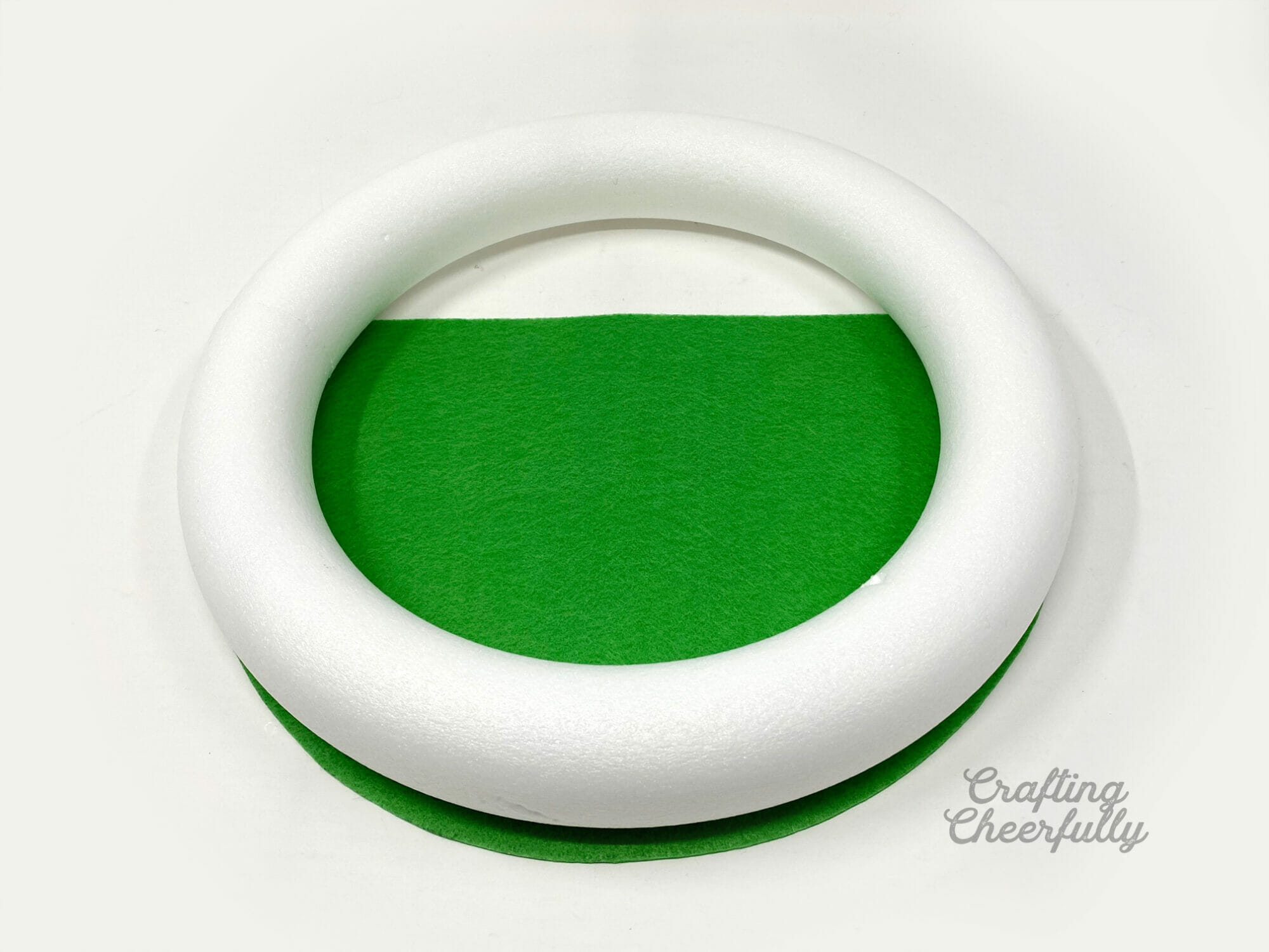 A sheet of green felt is cut to match the curve of the wreath form.