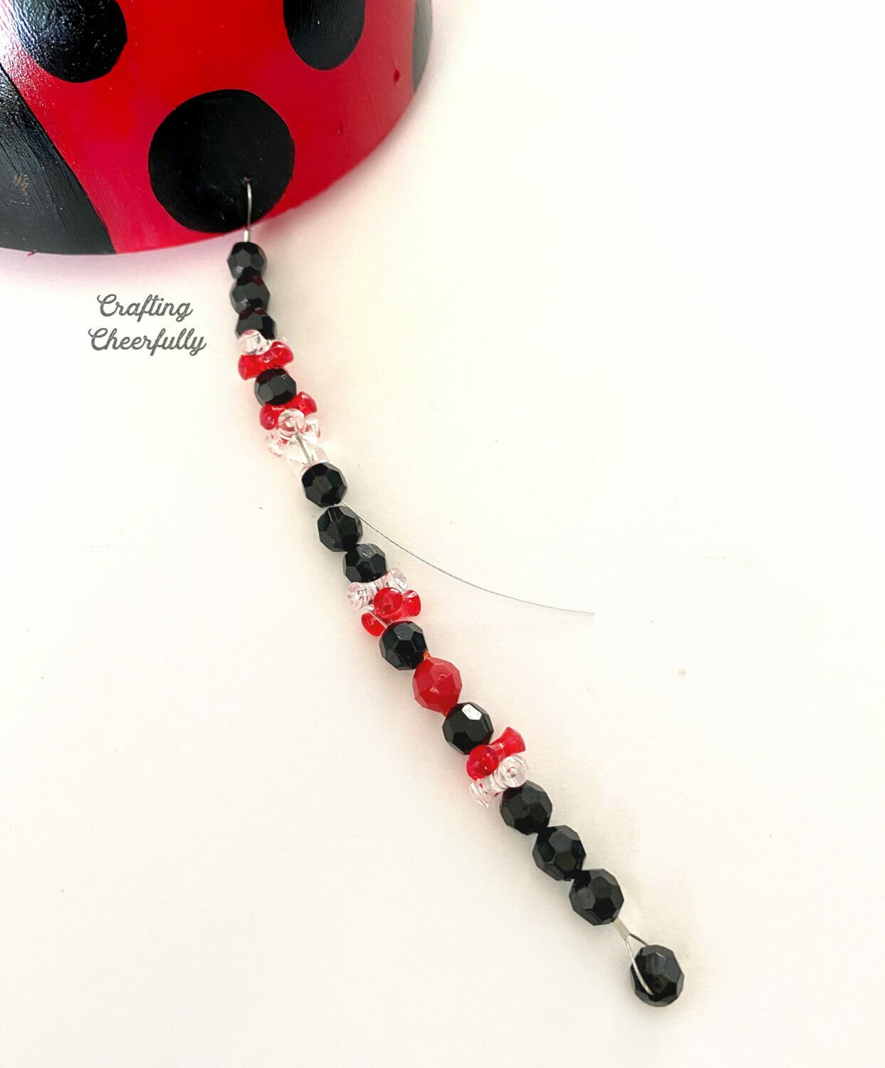 A beaded ladybug leg is attached to the ladybug bowl.