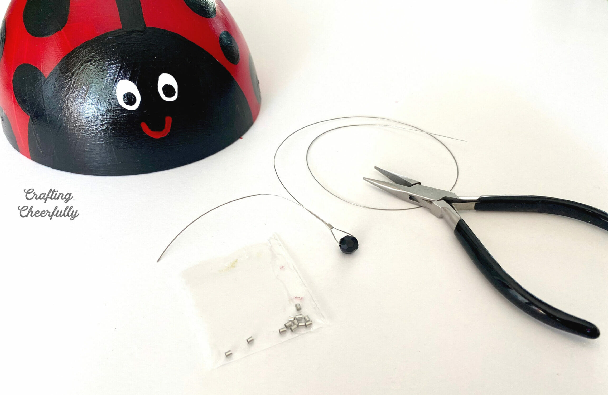 A black bead is threaded onto beading wire and a clamp bead holds it in place.