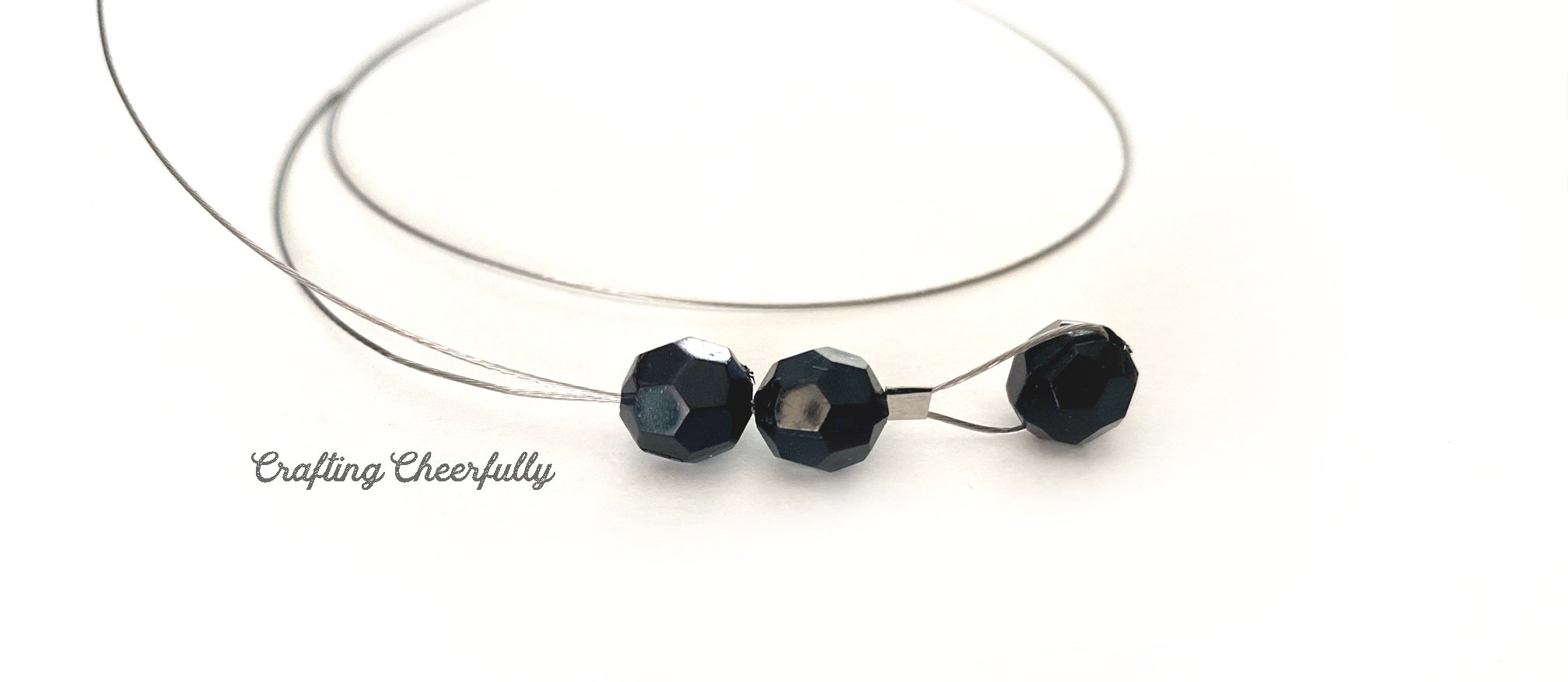Two black beads are strung on the wire on top of the crimping bead.