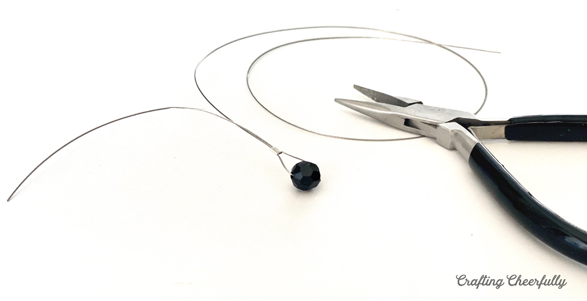 A black bead is threaded onto beading wire and a clamp bead holds it in place.
