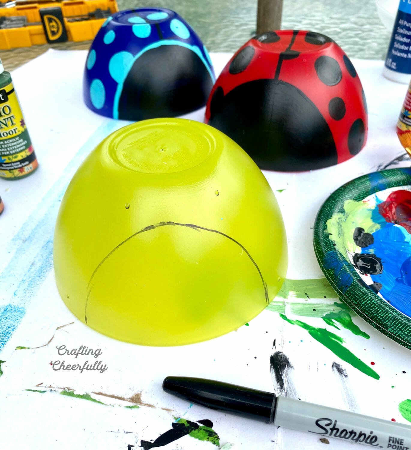 Three plastic bowls, a blue and red one look like ladybugs; the third yellow one has a semi-circle drawn on the front.