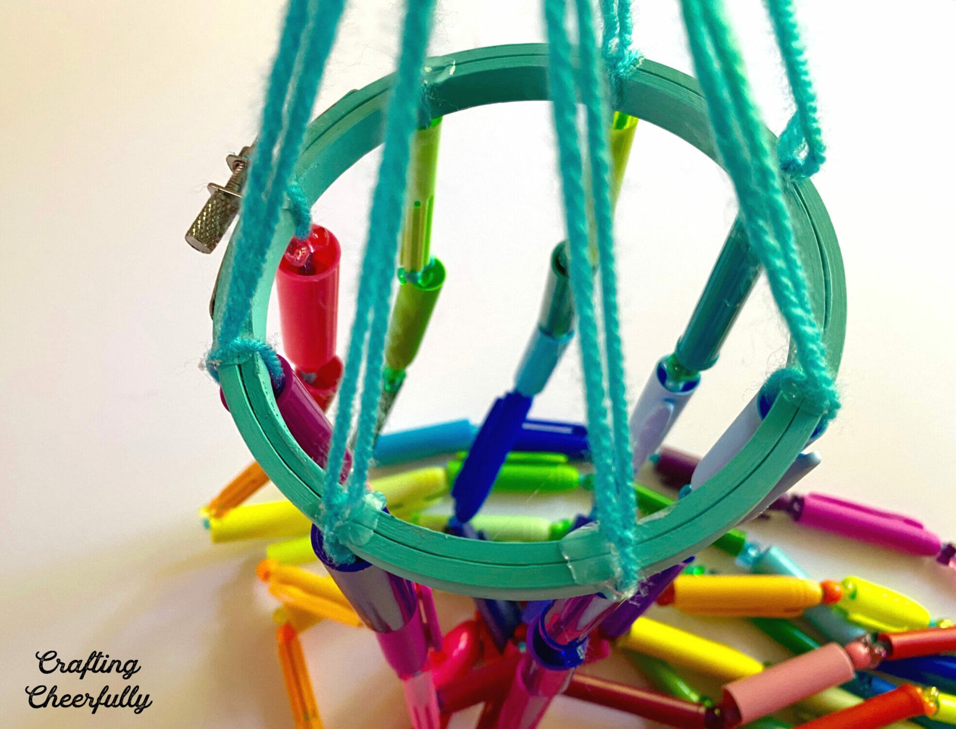 Top view of the wind chime showing the eight strands of marker caps attached to the embroidery hoop.