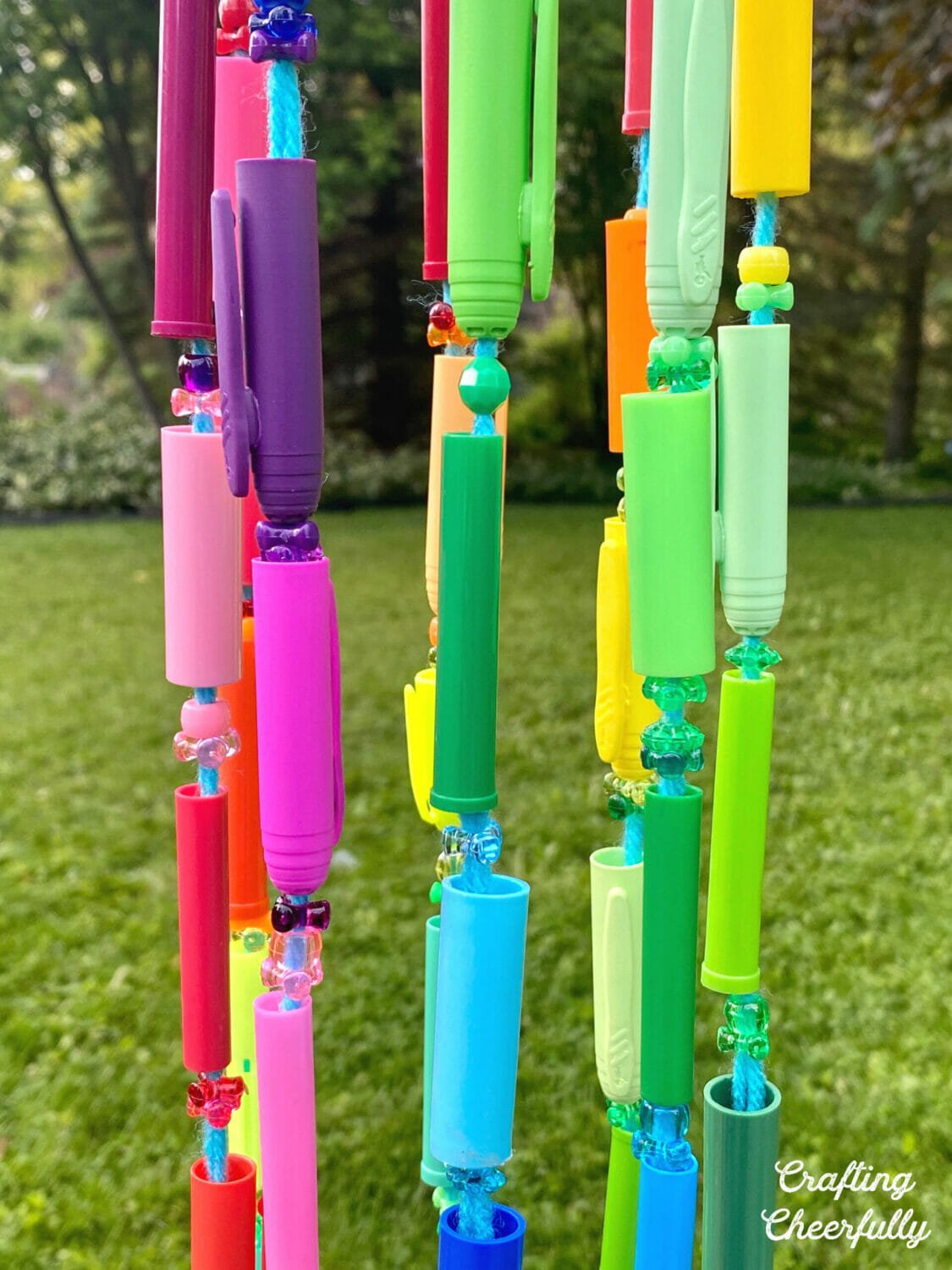 Colorful marker caps with sparkly beads create a wind chime.