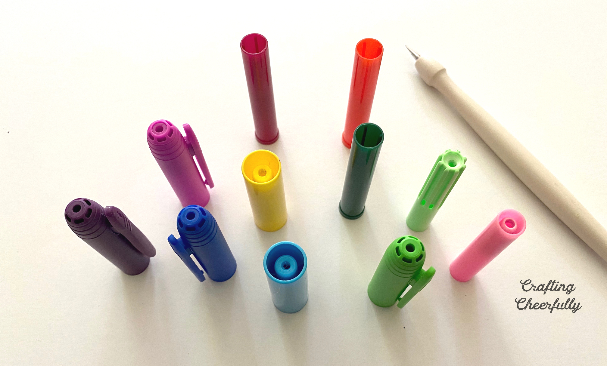 Marker caps on a table with holes punched into the top of each one.