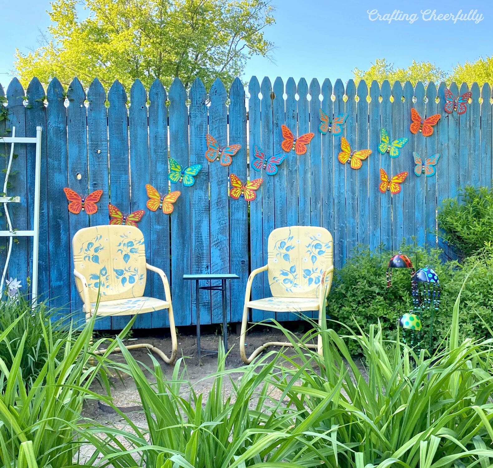 Colorful 3D butterflies hang on a blue fence.