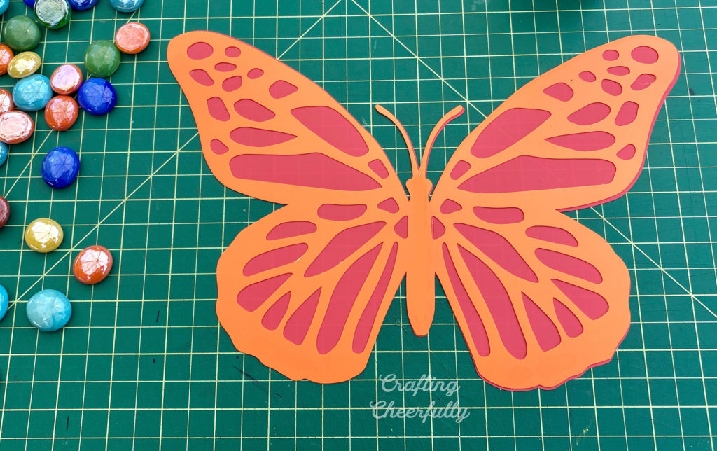 Butterfly cut from orange and red plastic dividers; the top orange layer has cut outs revealing the red layer.