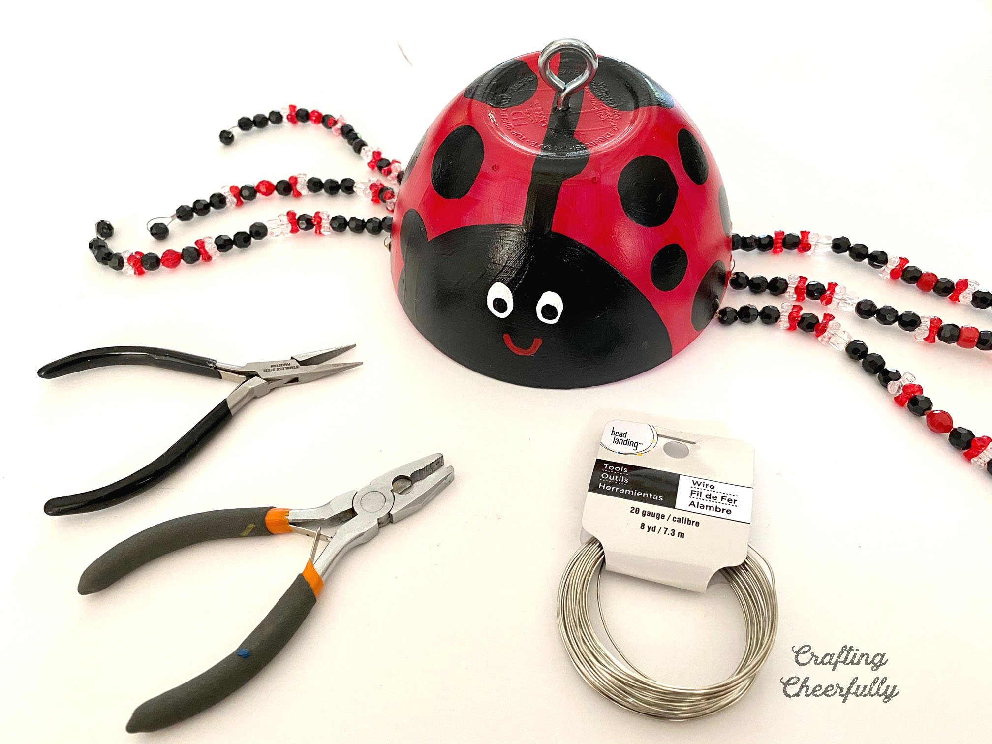 Wire antennae are added to a red ladybug.