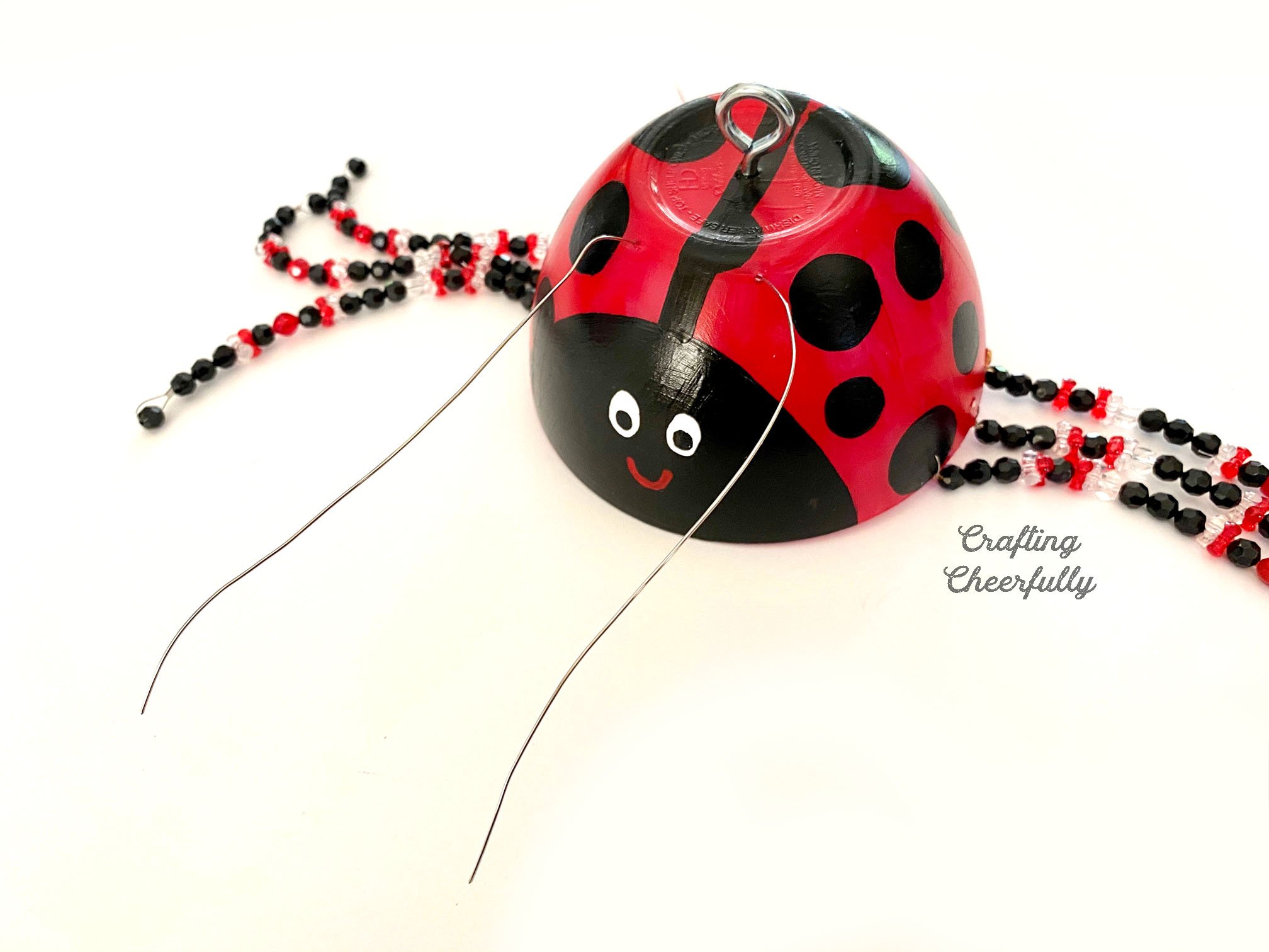 A long piece of wire is passed through the two holes in the front of the ladybug's head.