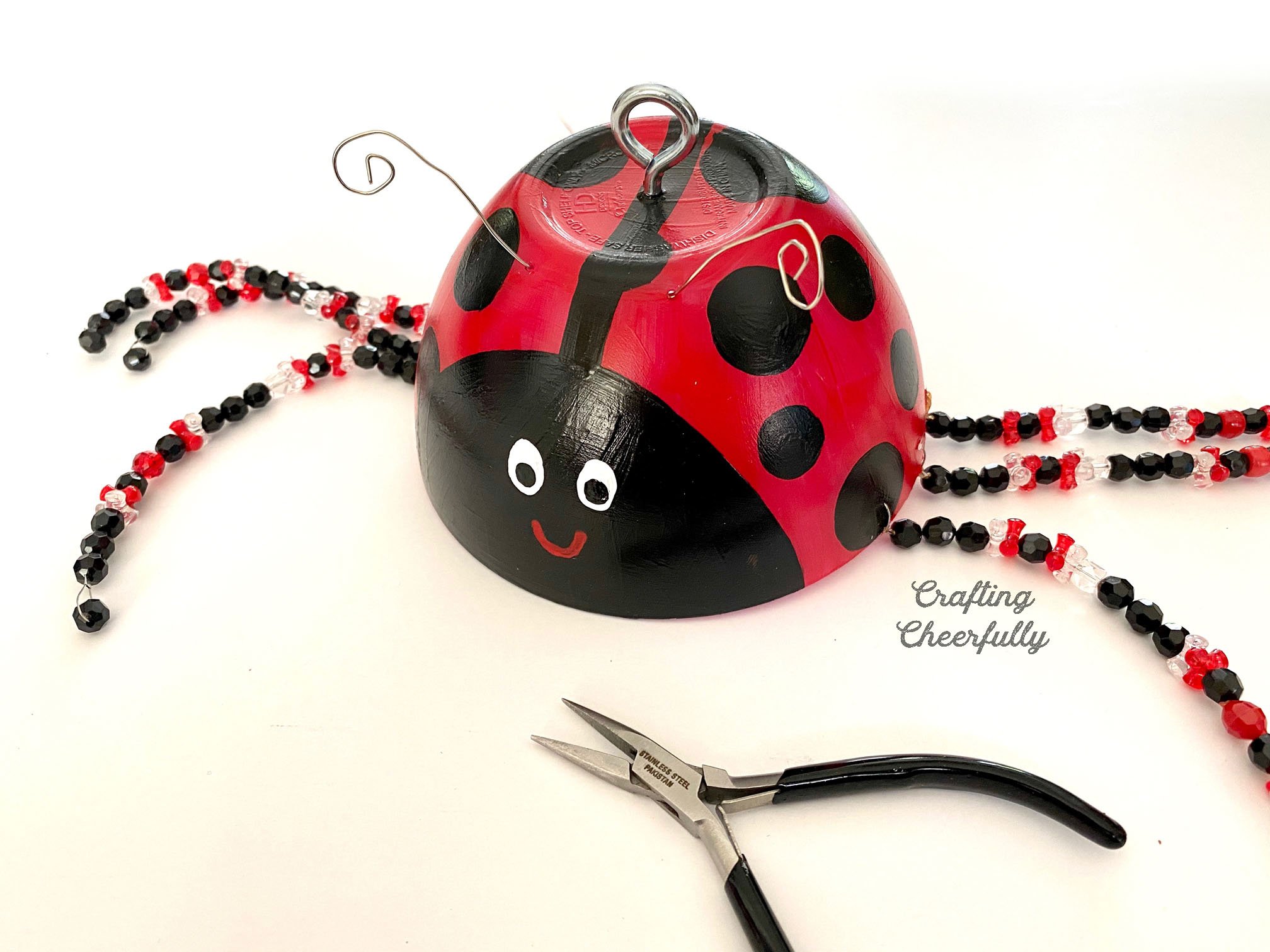 Ladybug garden ornament with curly wire antennae.