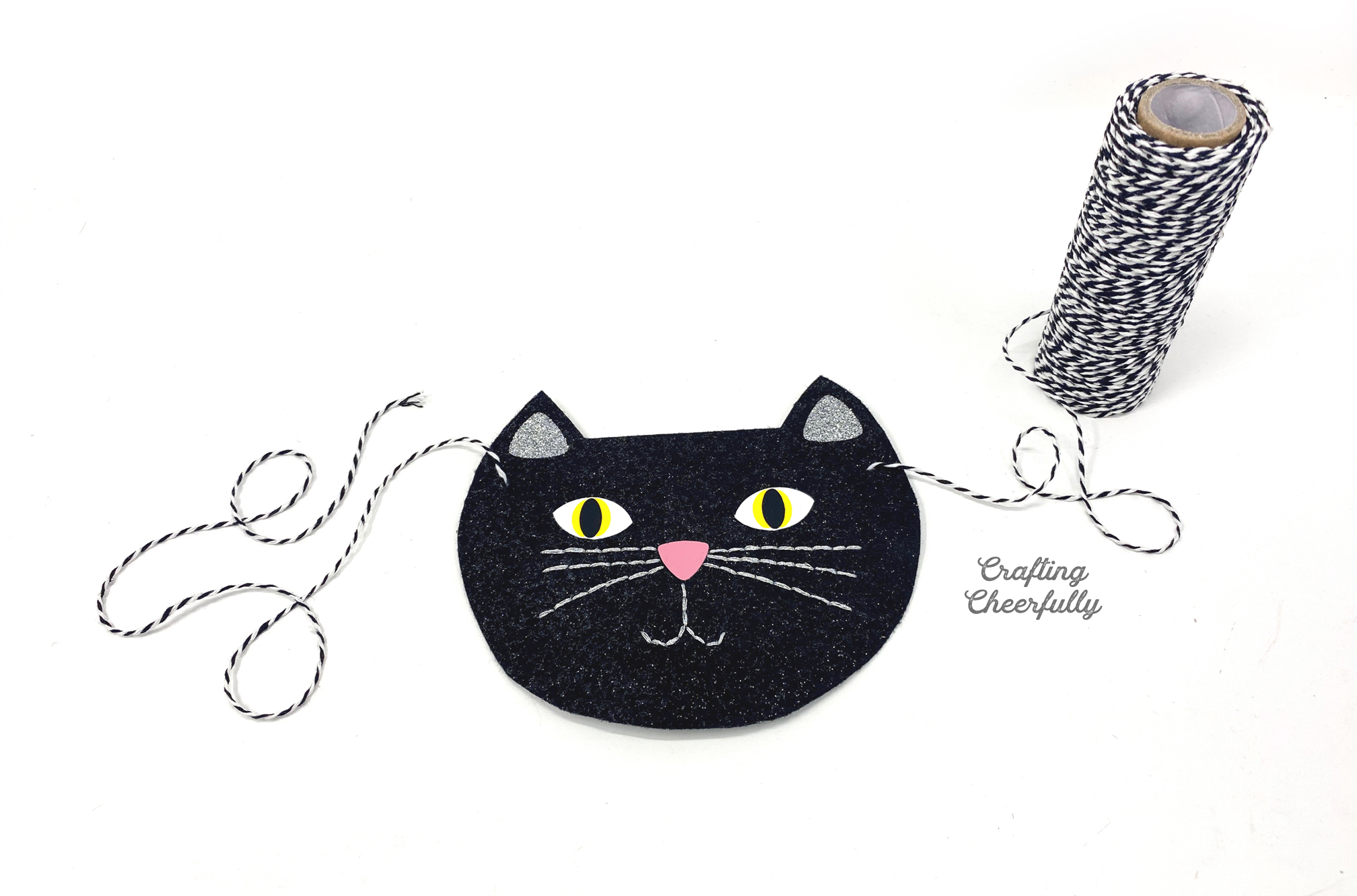Baker's Twine is threaded through the two holes on either side of one of the cat pennants.