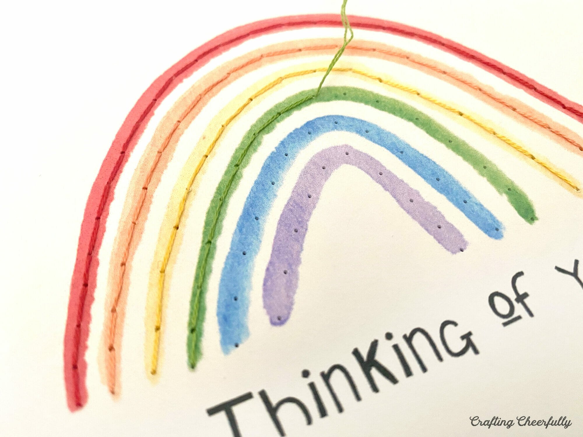 Green embroidery floss is used to stitch along the green part of the rainbow card.