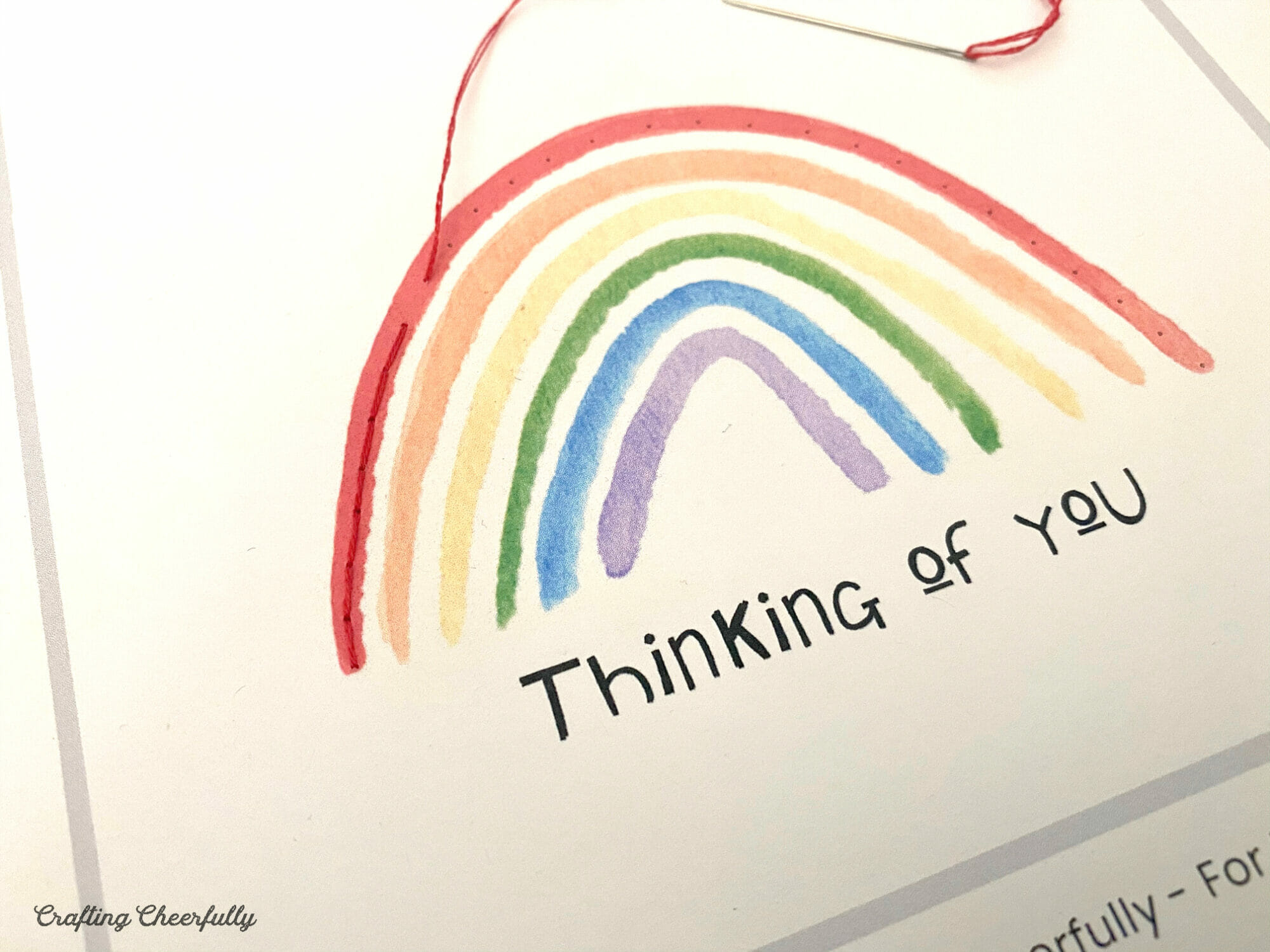 Red embroidery floss is used to stitch along the rainbow.