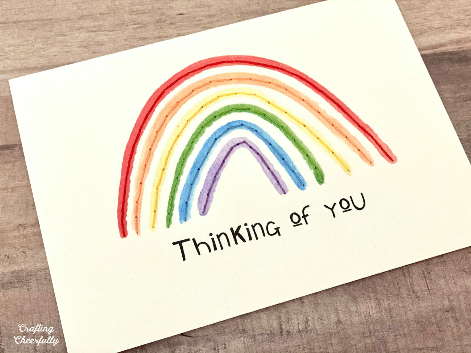 Rainbow card that reads "Thinking of You" with stitching along the rainbow colors.