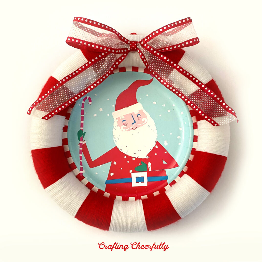 A red and white wreath with a Santa Claus plate in the center.