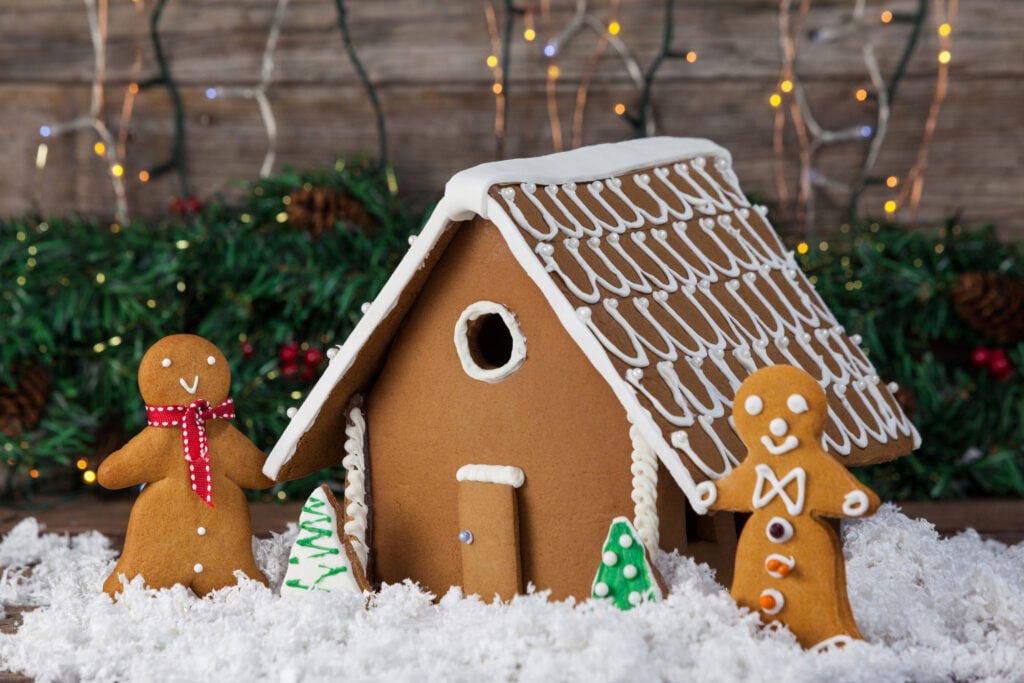 Gingerbread house with two gingerbread people next to it.