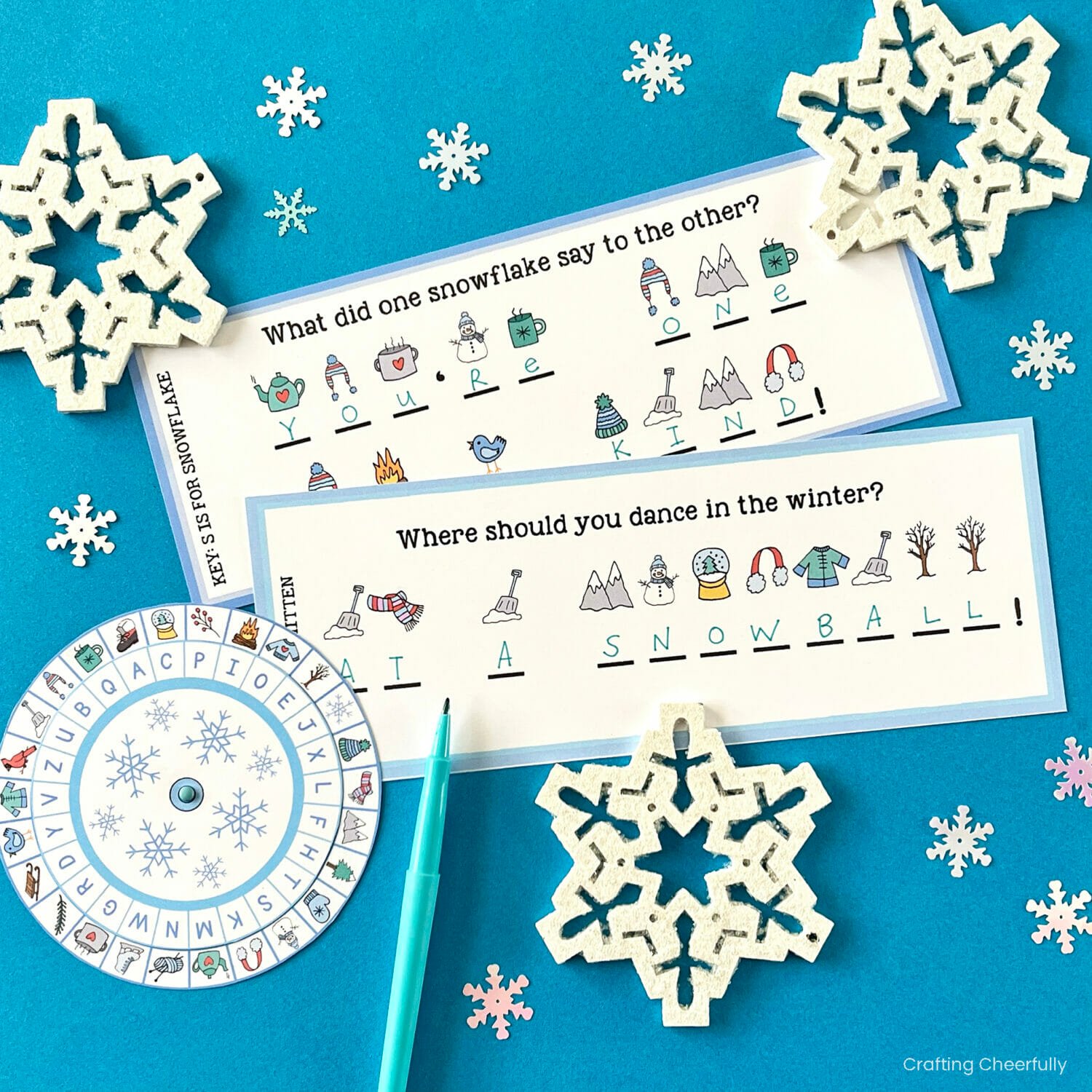 Winter themed riddles written in code lay next to a winter cipher wheel.