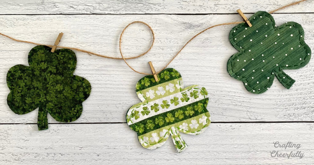 Three fabric shamrocks are clipped to a piece of twine with mini clothespins.